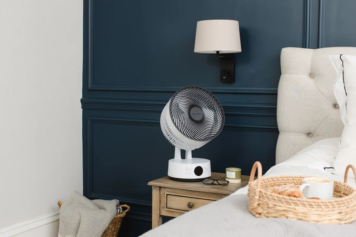 MeacoFan Sefte 10-inch in table mode on a bedside table next to a bed